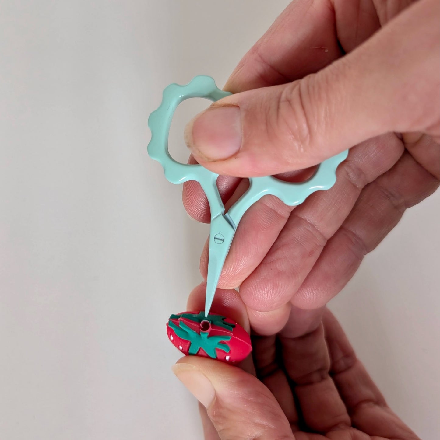 Hands holding teal snip and inserting into topper.