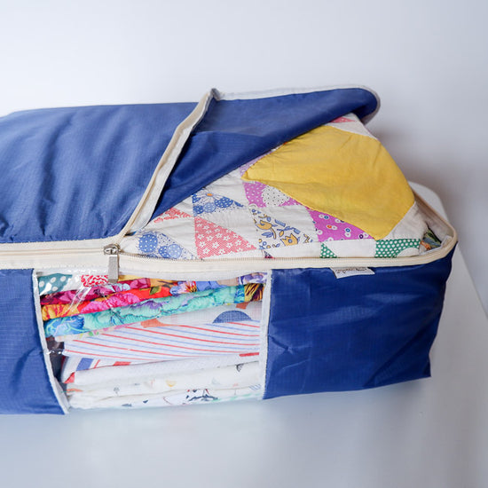 Colorful quilt inside a blue quilt storage bag on a white table