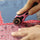 women using a pink 28 mm rotary cutter to cut red fabric with a ruler