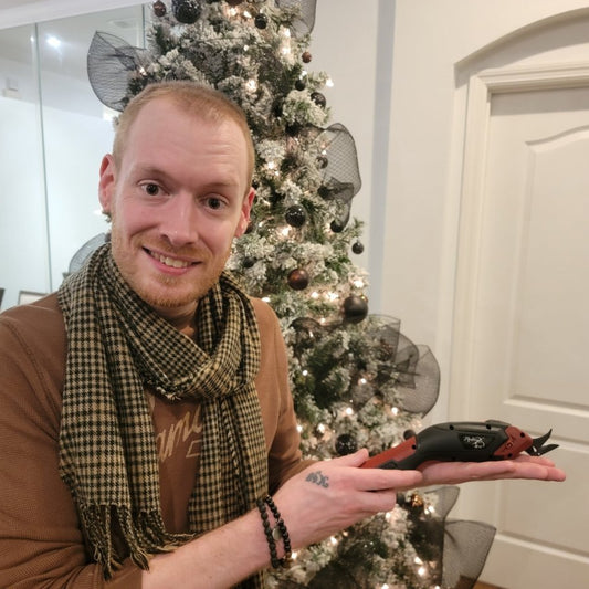 Young guy holding Madam Sew's Electric Fabric Scissors in a holiday interior