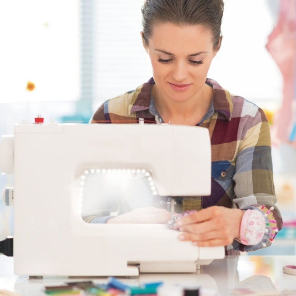 A women sewing with a wite sewing machine that is lit up by a light strip
