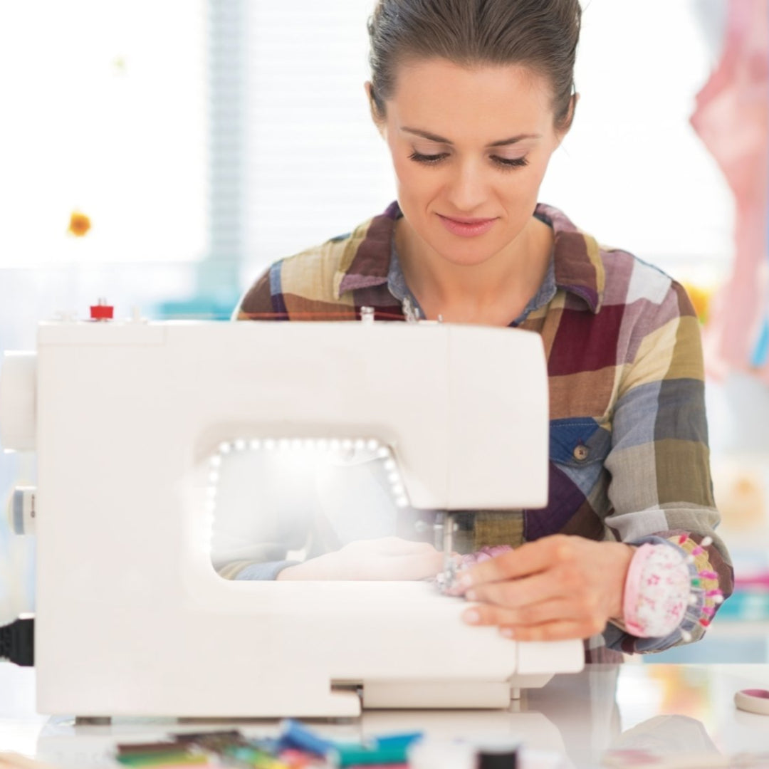 A women sewing with a wite sewing machine that is lit up by a light strip