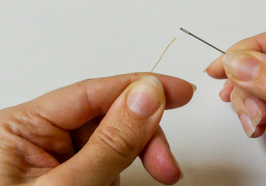 hands holding needle and thread