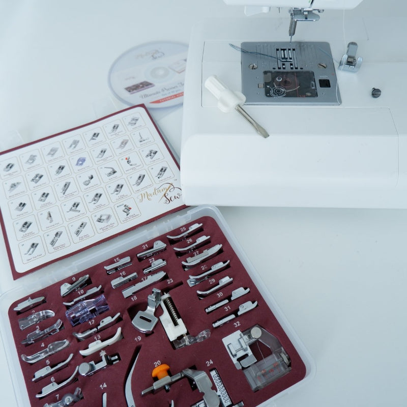 a sewing machine on a white table with a box of presser feet next to it and a screw driver to attach the screw-on feet