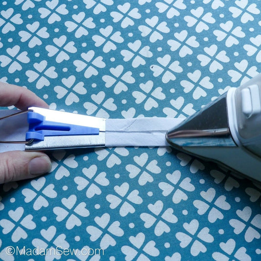 Ironing bias tape as it comes out of the blue bias tape maker.