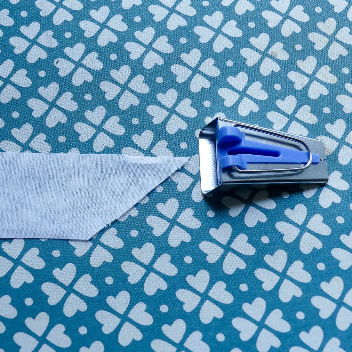 Blue Bias Tape Maker and a fabric strip ready to be fed into it.