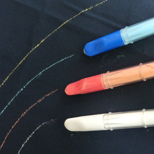 three chalk markers marking on dark fabric