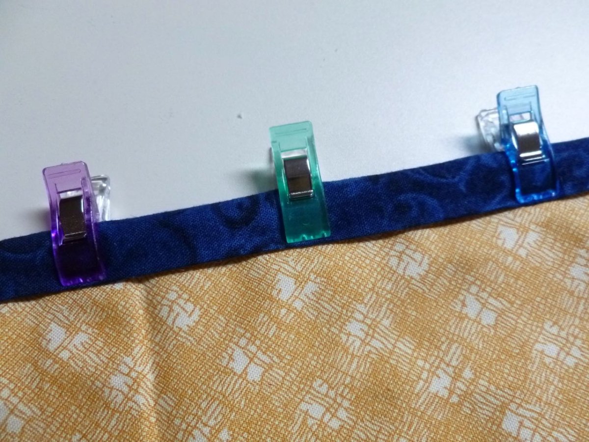 sewing clips on blue bias tape and yellow fabric with white design
