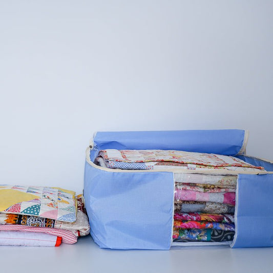 Purple quilt storage bag with a pile of quilts next to it