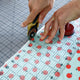 hands cut fabric with a rotary cutter and a ruler