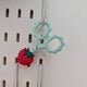 Teal snips with cover hanging up on pegboard