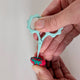 Hands holding teal snip and inserting into topper.