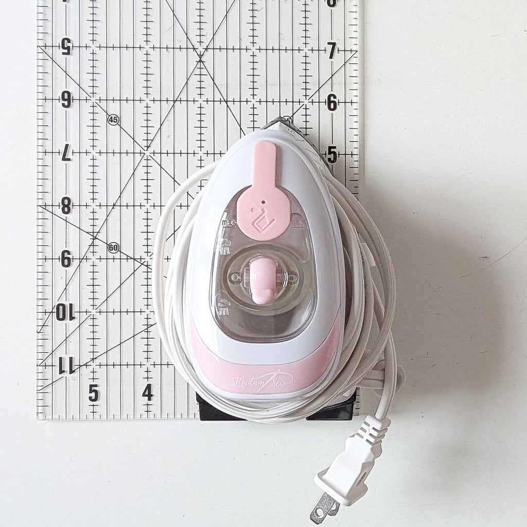 Madam Sew Mini Iron on a ruler to show size.