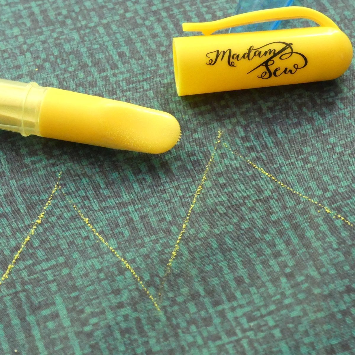 detail of a yellow chalk marker, yellow chalk lines and the cap with brand Madam Sew