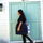 Woman walking past pale green doors carrying a navy quilted sewing machine bag on her shoulder