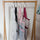 White, black, pink and burgundy mesh project bags hanging from hooks on a wooden rail