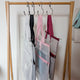 White, black, pink and burgundy mesh project bags hanging from hooks on a wooden rail
