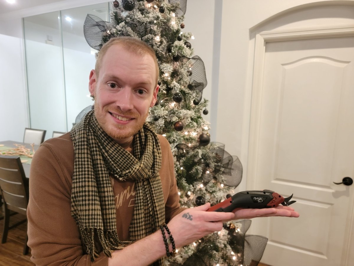 Young guy holding Madam Sew's Electric Fabric Scissors in a holiday interior