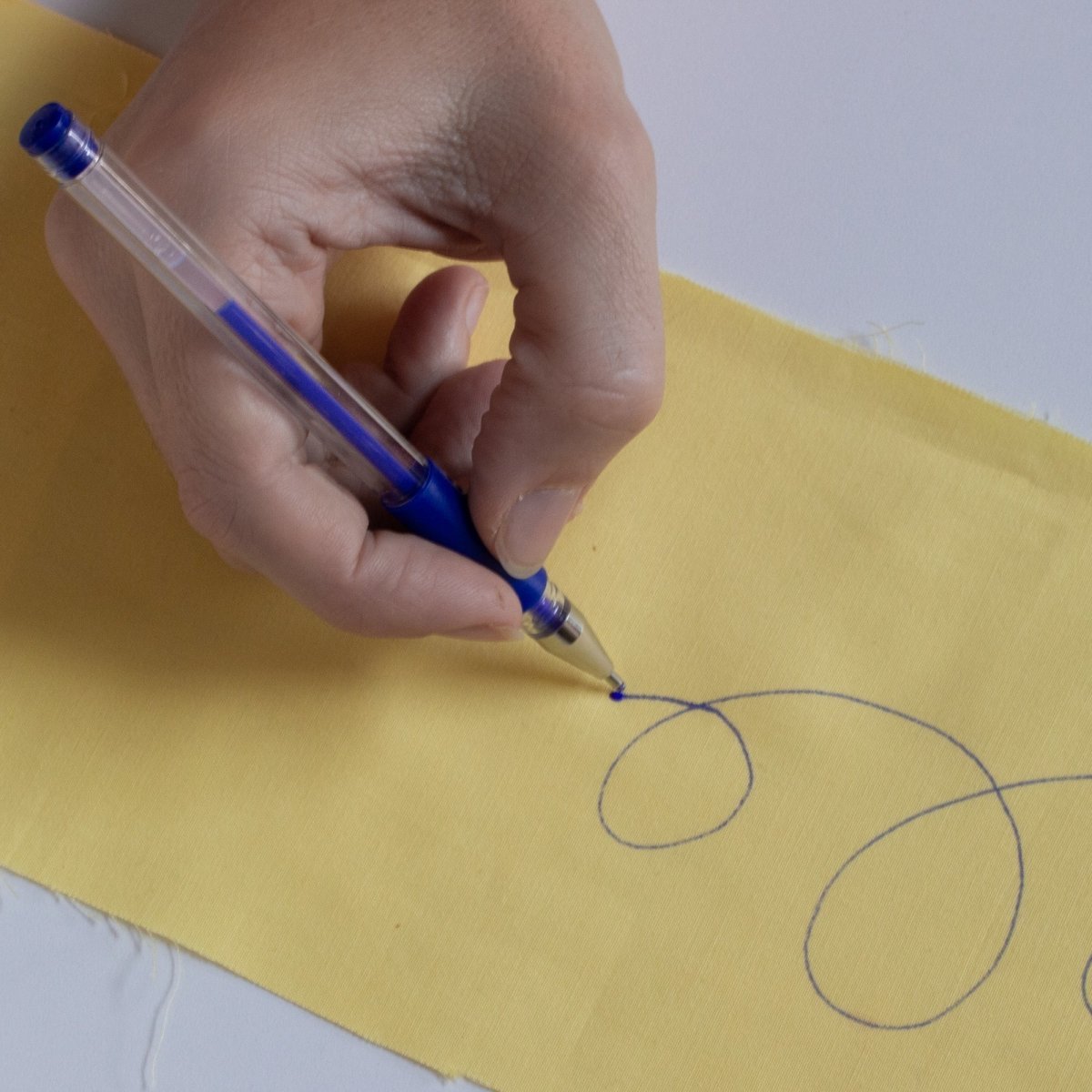 writing with a blue fabric marker on yellow fabric