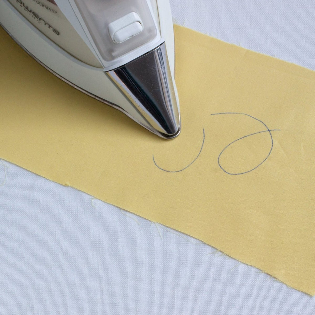 erasing a fabric mark with a hot iron on yellow fabric
