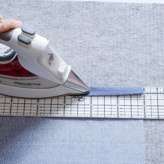 Someone uses a hot hem ruler  and iron to iron a hem on dotted fabric