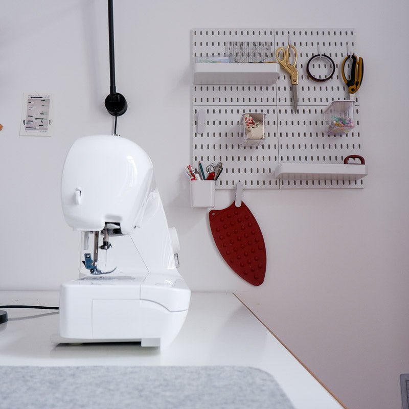 Peg board on a wall in a sewing room