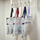 Six mesh project bags with different coloured trims hanging from hooks on a rail