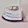 Pink and white Madam Sew mini iron sitting in its pink iron rest