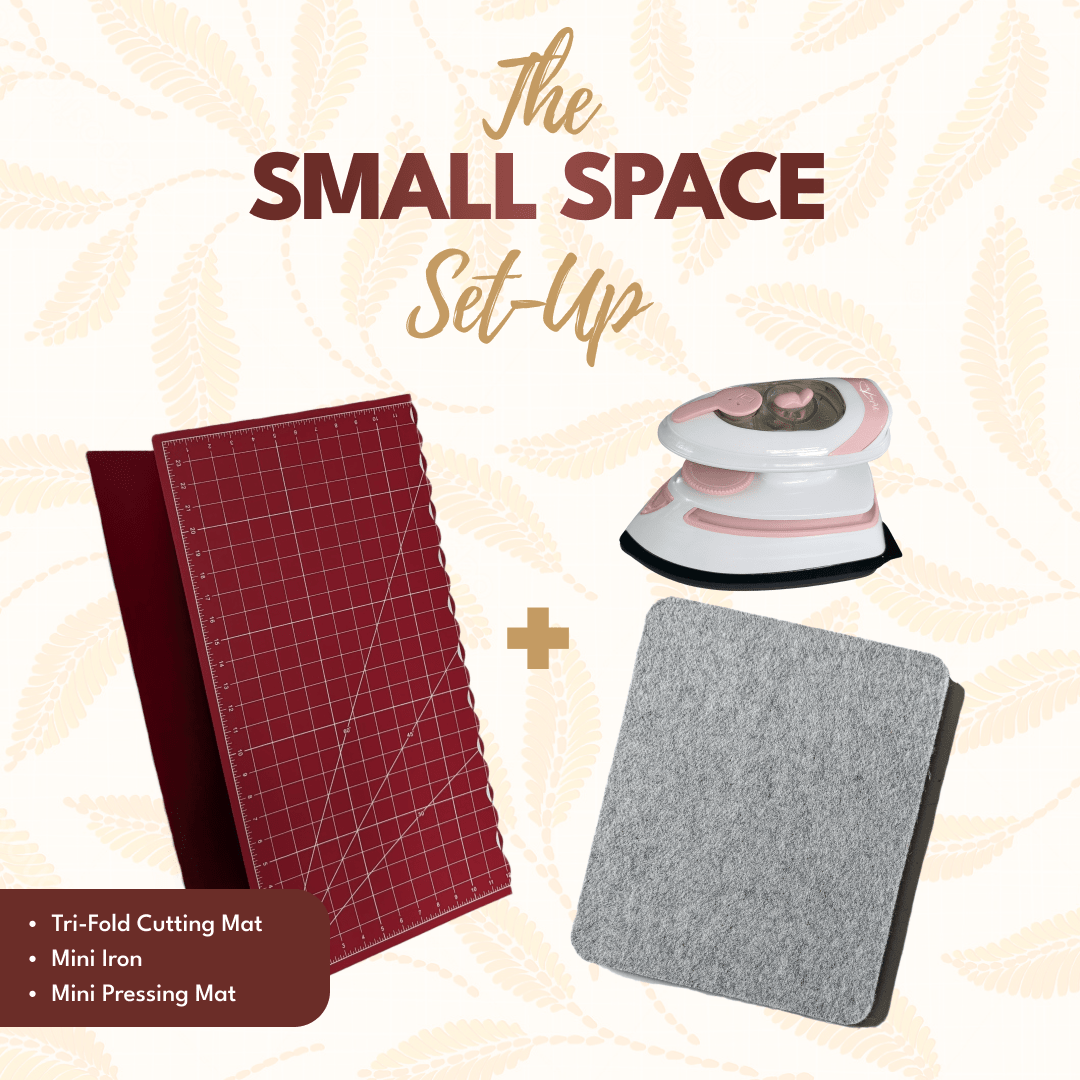 Small space setup graphic with red tri-fold cutting mat, pink and white mini iron and grey wool pressing mat