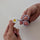 Hands sliding the daisy silicone cover onto the tip of lilac sewing snips