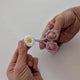 Hands sliding the daisy silicone cover onto the tip of lilac sewing snips
