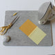Wool Pressing Mat on a table with scissors, an iron, a pincushion, seam ripper and some fabrics