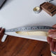 Peeling back the backing on the Adhesive Ruler Tape to apply to work surface.