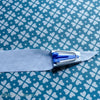 The point of a fabric strip coming out of the blue bias tape maker.