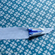 The point of a fabric strip coming out of the blue bias tape maker.