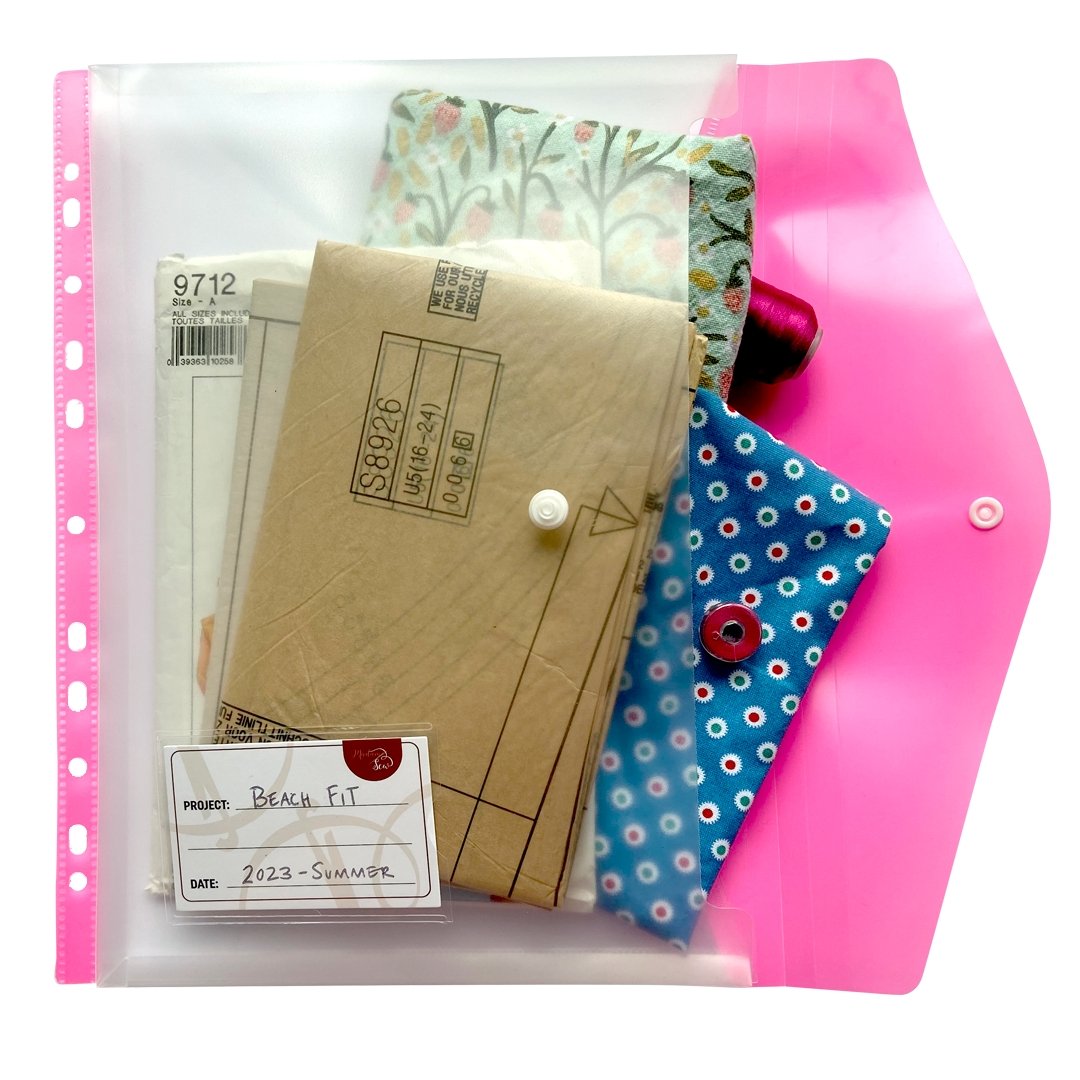One organization sewing room binder pocket in color pink holding sewing patterns, fabric and thread