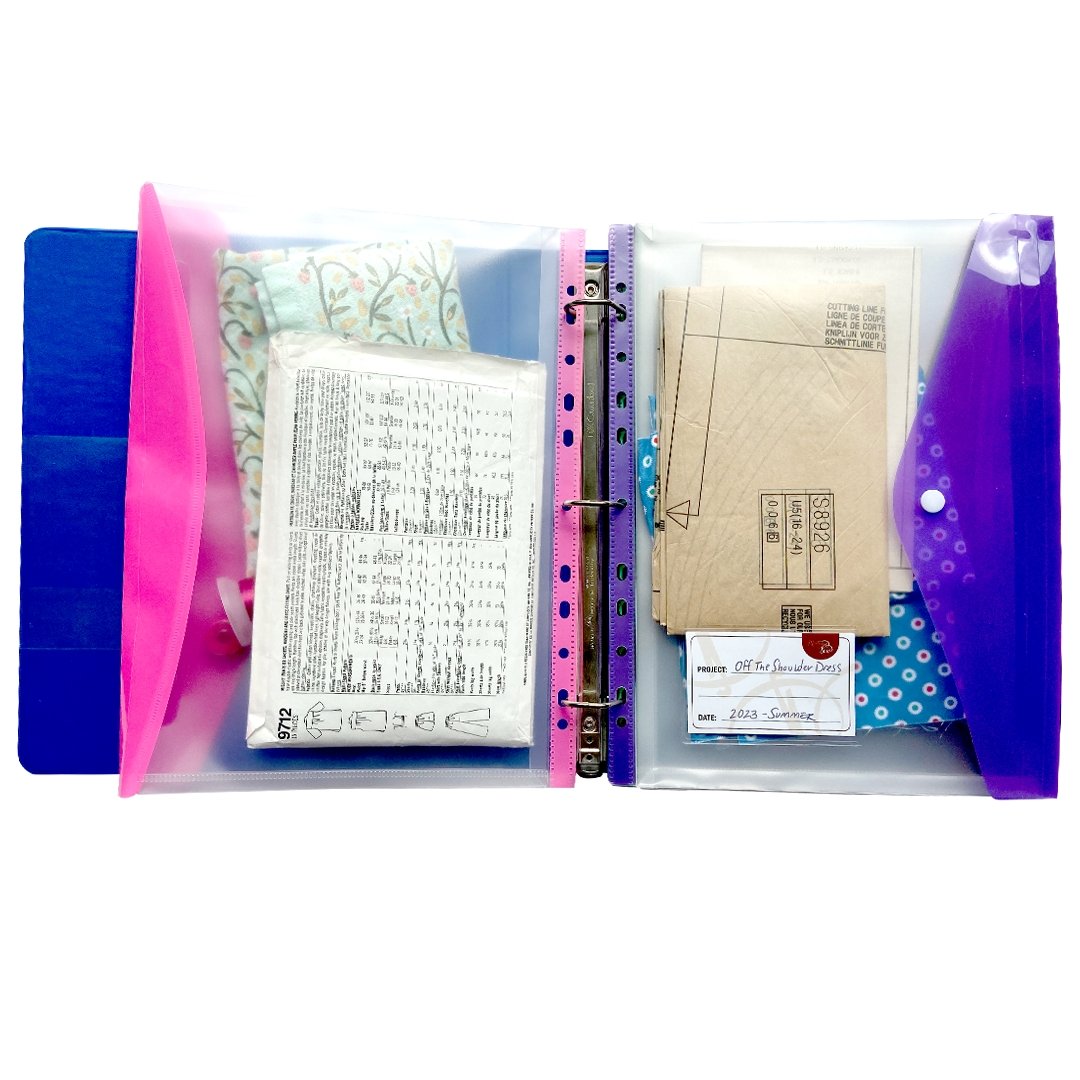 Two organization sewing room binder pockets in purple and pink holding sewing patterns, fabric inserted into a blue binder.