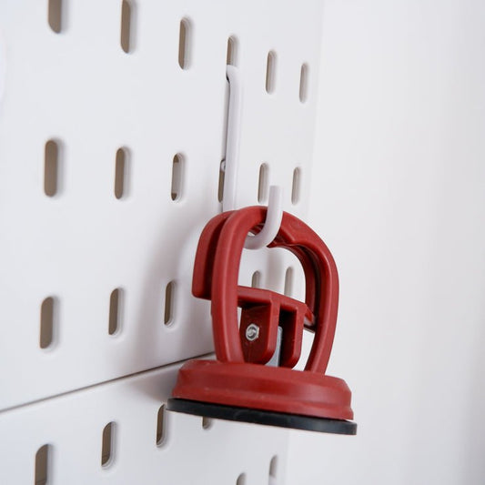 A hook on a peg board with a ruler grip hanging from it