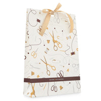 A white sewing-themed gift wrapping bag