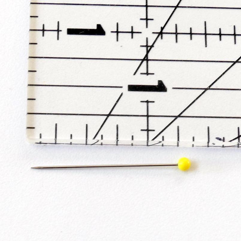 Glass Head Pin next to a ruler showing that it is 1 1/4" long.