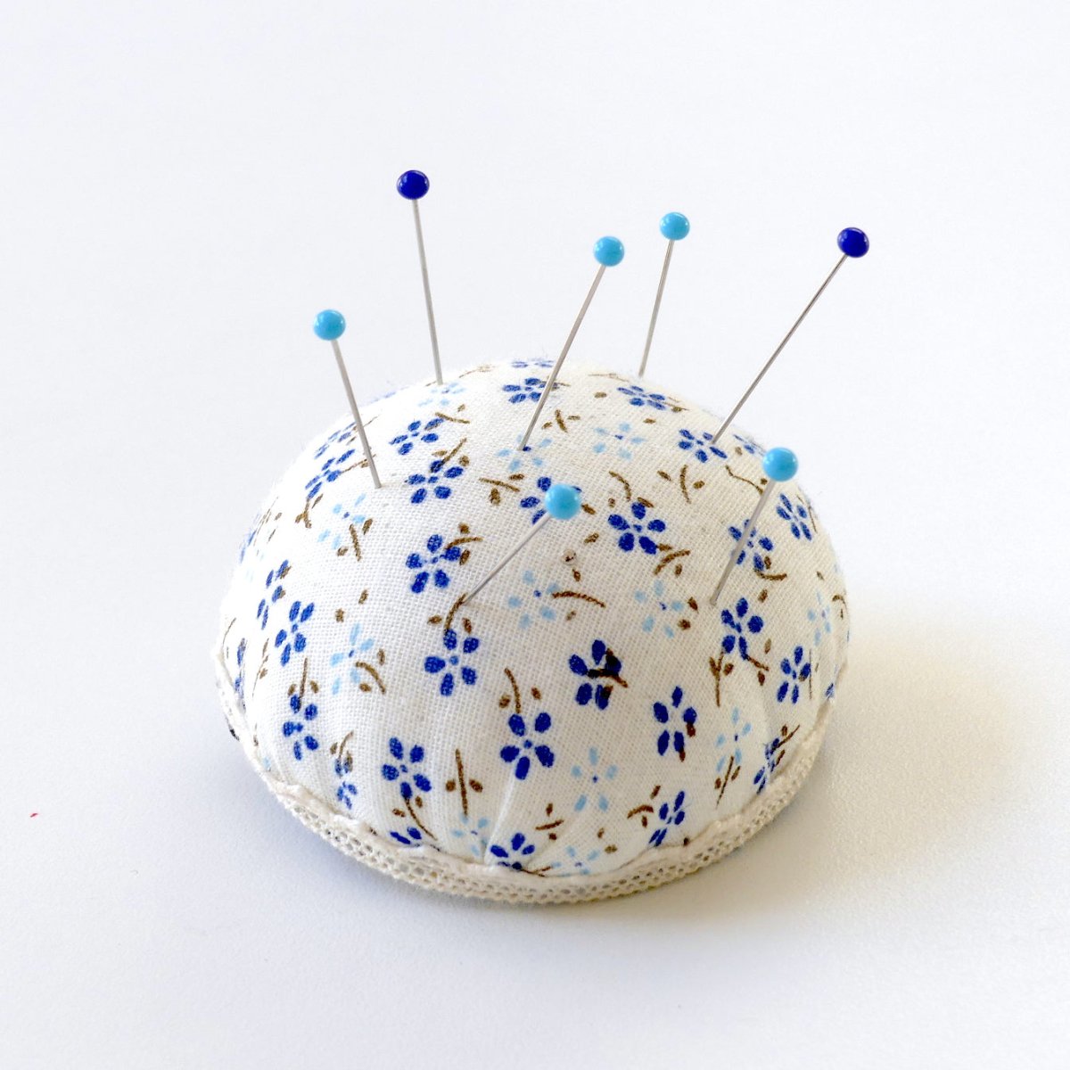 Glass Head Pins poked into a pin cushion.
