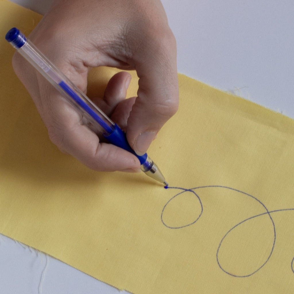 Drawing with a blue Heat Erasable Fabric Marking Pen on yellow fabric