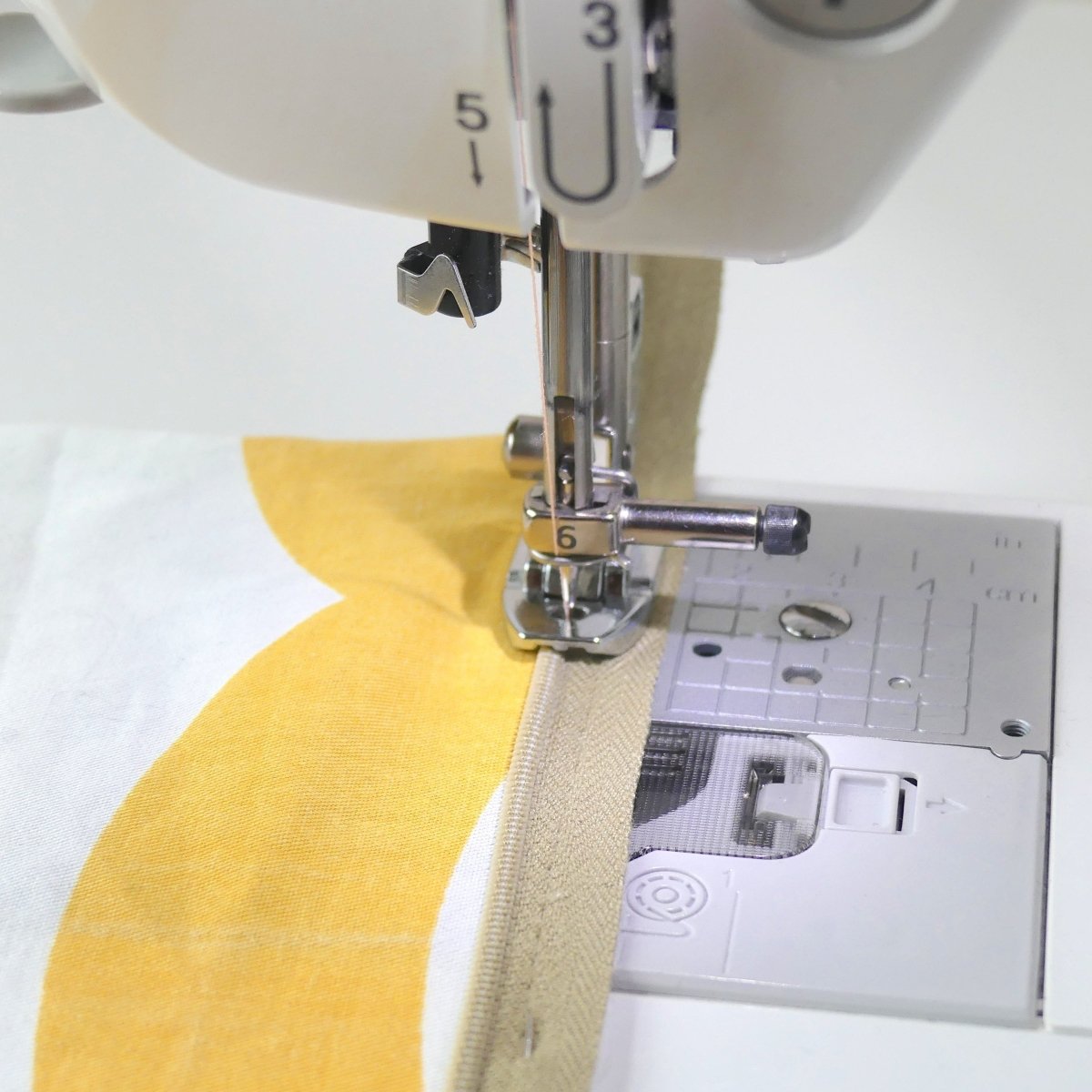 The Invisible Zipper Foot being used to sew an invisible zipper to a piece of fabric on the right.