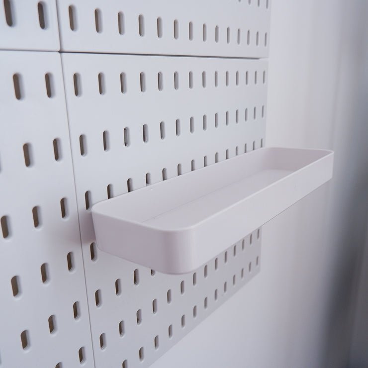 White long plastic tray attached to a peg board