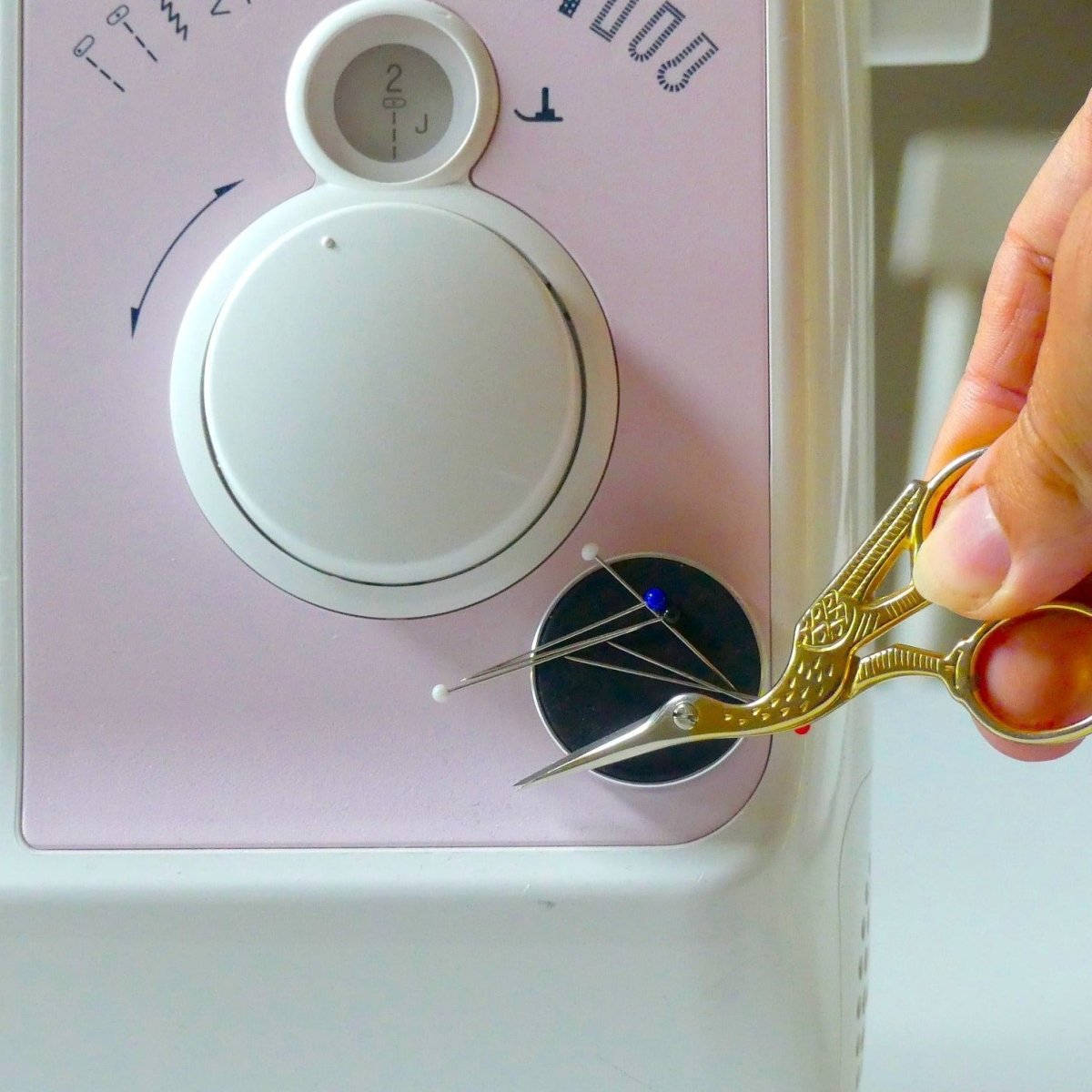 Magic Holder on a sewing machine holding pins and small stork scissors.
