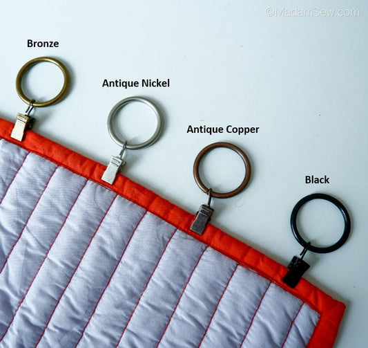 The four colors of Metal Curtain & Quilt Hangers displayed at the top of a quilt.