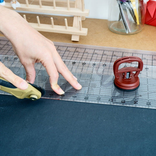 Quilting ruler with a hand that pushes on the cutter to cut fabric with a rotary cutter