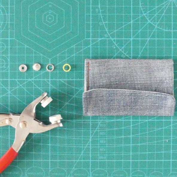 Picture of the pieces that are part of the open ring snap button, pliers and fabric pouch.