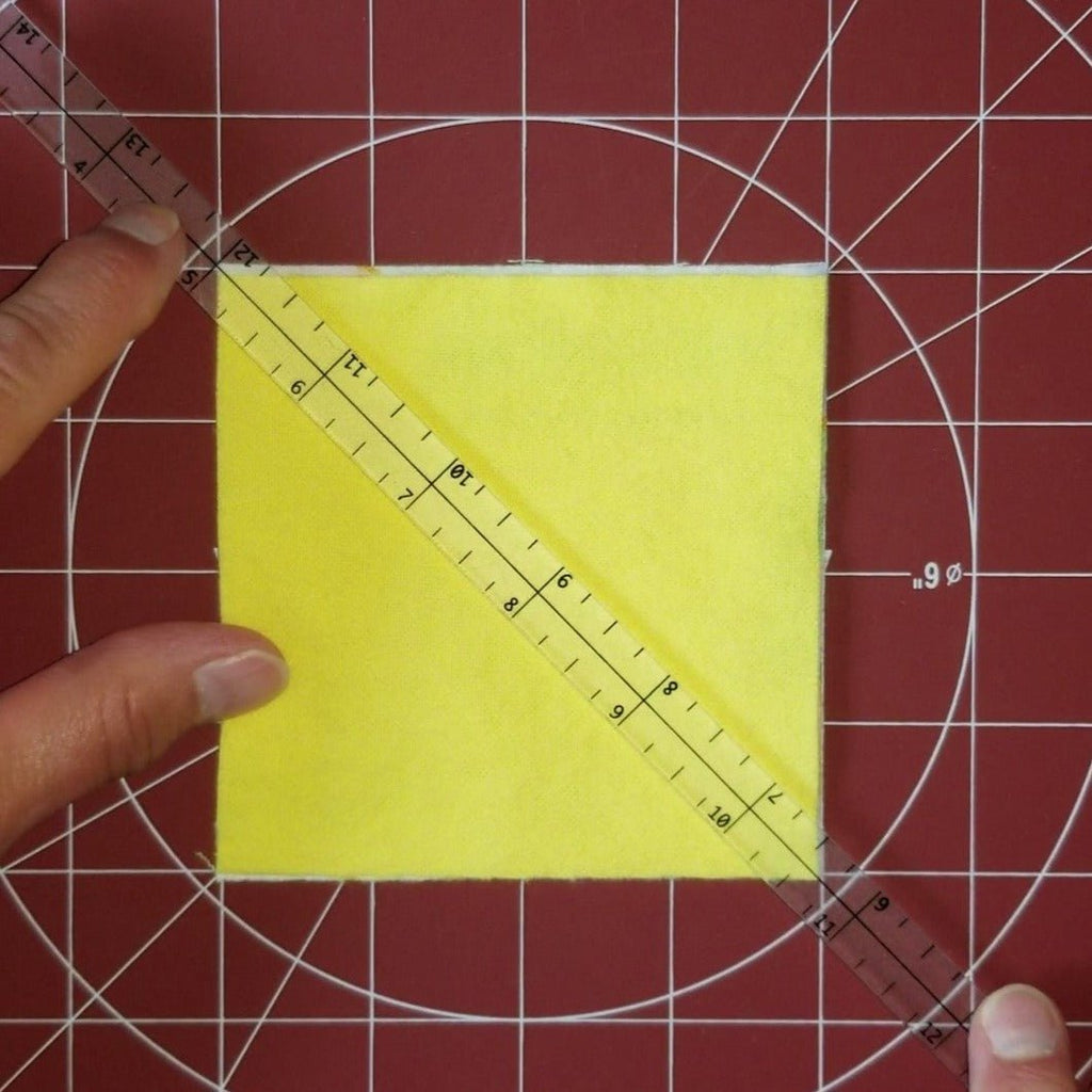 Showing lining Quarter Inch Patchwork Ruler "QIP" on a fabric square, corner to corner