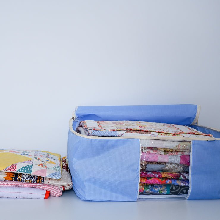 Purple quilt storage bag with a pile of quilts next to it